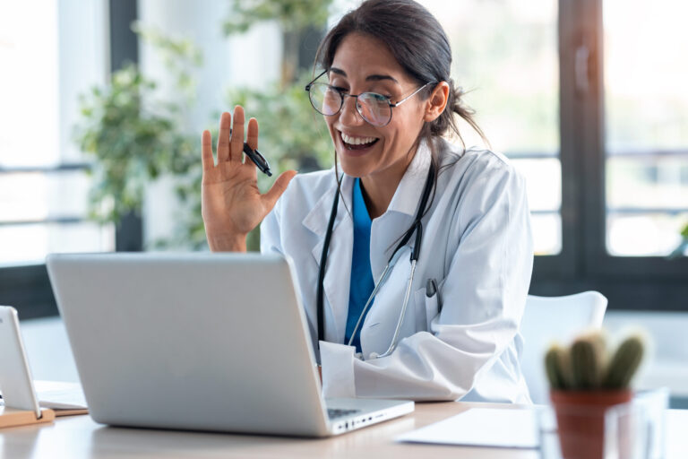 Female doctor waving and talking with colleagues through a video